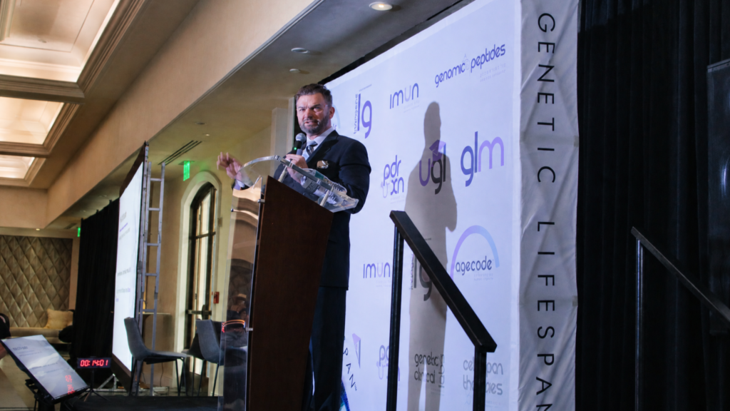 Genetic LifeSpan CEO Adam Vincent Gilmer smiling during a professional media interview, captured in a brightly lit indoor setting.